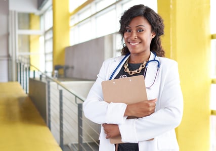 Portrait of a female doctor holding her patient chart in bright modern hospital
